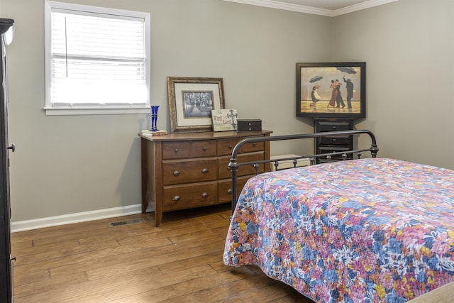  - bedroom featuring baseboards, visible vents, wood finished floors, and ornamental molding
