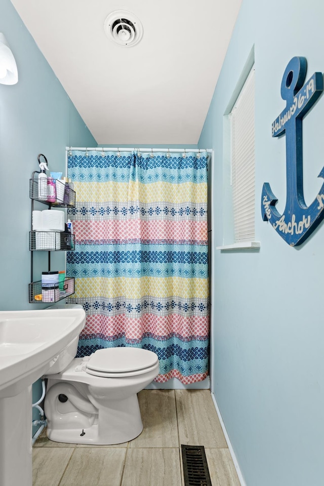 bathroom featuring toilet and curtained shower