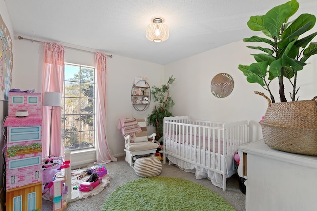 carpeted bedroom with a textured ceiling and a nursery area