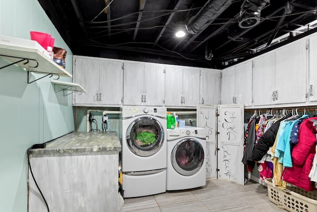 laundry room with washing machine and clothes dryer and cabinets