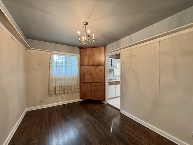  - unfurnished dining area featuring a chandelier and wood finished floors