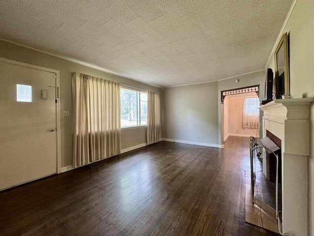 - unfurnished living room featuring dark wood-type flooring, a fireplace with raised hearth, and ornamental molding