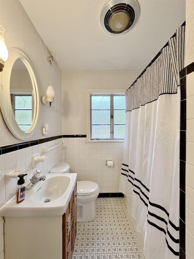  - full bathroom featuring vanity, tile patterned floors, tile walls, wainscoting, and curtained shower