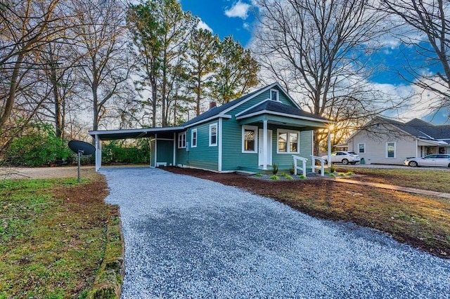  - view of front of house featuring driveway, a carport, a porch, and a chimney