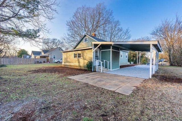  - view of home's exterior with a chimney, a carport, and entry steps