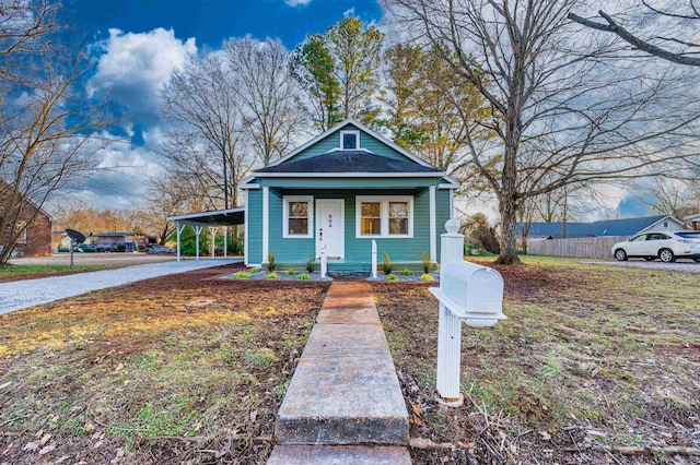 - view of front of house featuring an attached carport, gravel driveway, a porch, and a shingled roof