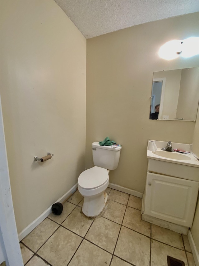 half bathroom with tile patterned floors, toilet, a textured ceiling, baseboards, and vanity