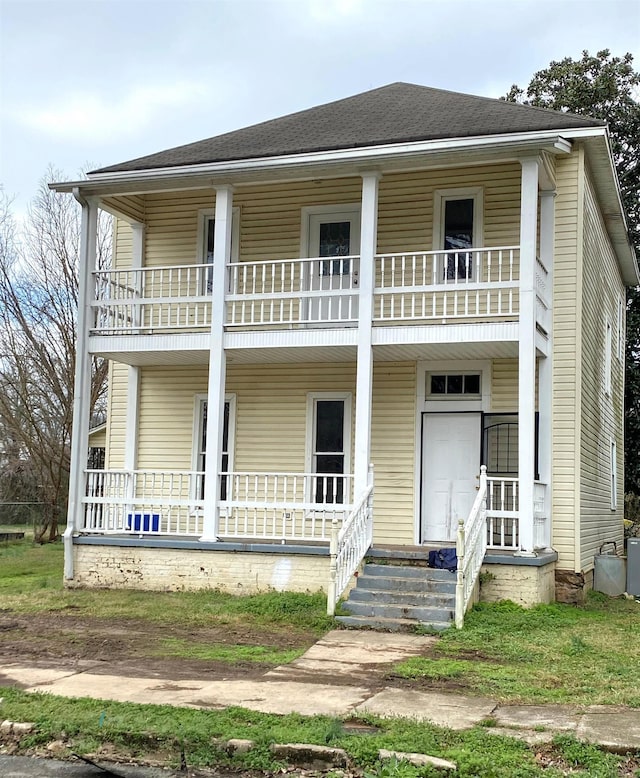 view of front facade featuring a balcony, covered porch, and roof with shingles