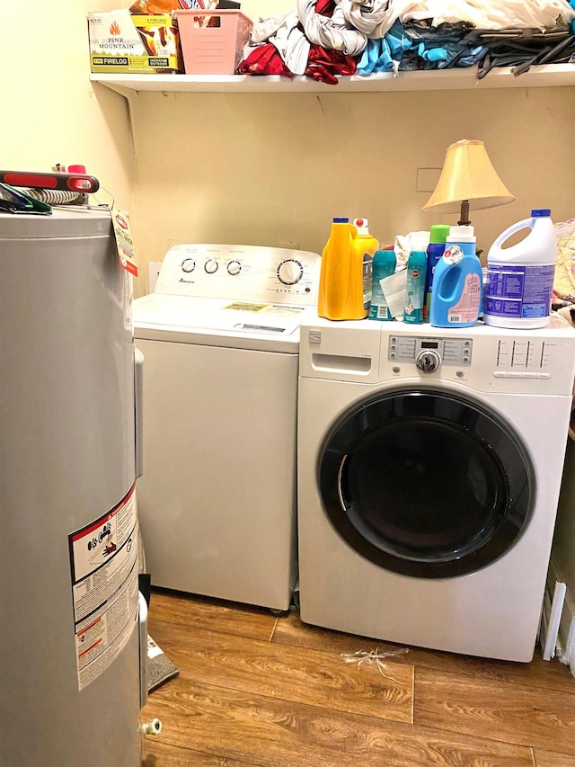 clothes washing area featuring water heater, laundry area, wood finished floors, and separate washer and dryer