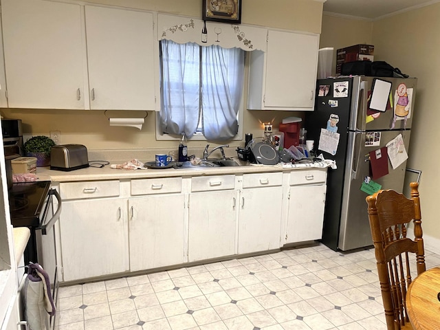 kitchen with freestanding refrigerator, ornamental molding, light countertops, electric stove, and white cabinetry