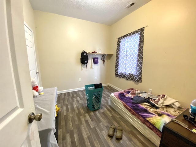 bedroom with visible vents, multiple windows, a textured ceiling, wood finished floors, and baseboards