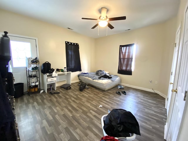 bedroom featuring ceiling fan, visible vents, baseboards, and wood finished floors