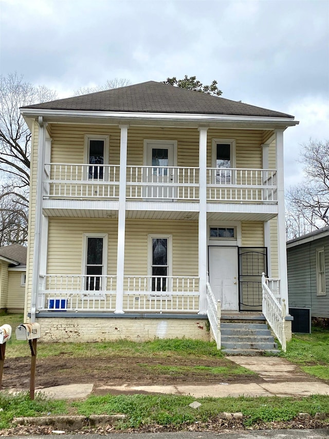 view of front of house featuring a porch, a balcony, and a shingled roof