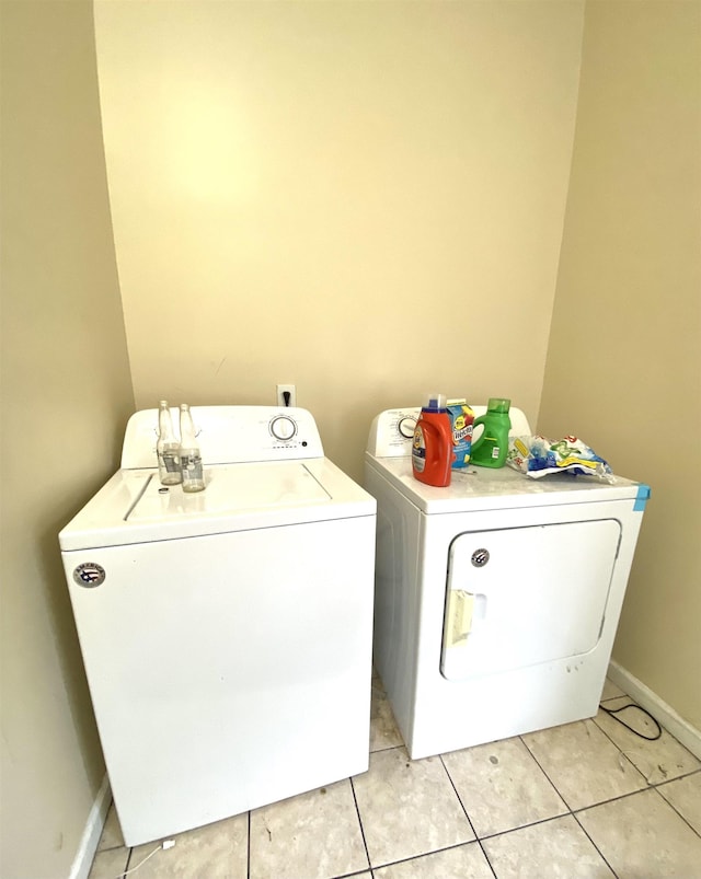 washroom with light tile patterned flooring, laundry area, washing machine and dryer, and baseboards