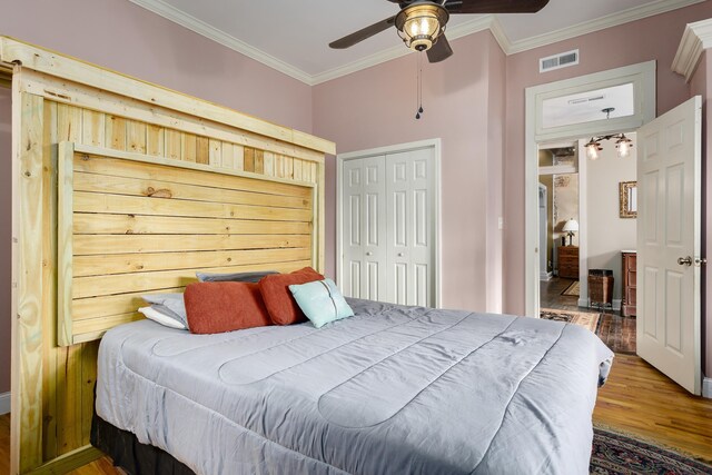  - bedroom featuring ceiling fan, wood finished floors, visible vents, ornamental molding, and a closet
