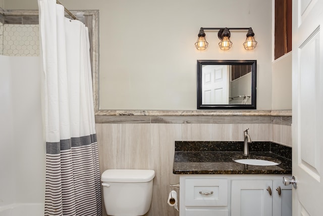  - full bath with toilet, vanity, tile walls, wainscoting, and a shower with curtain