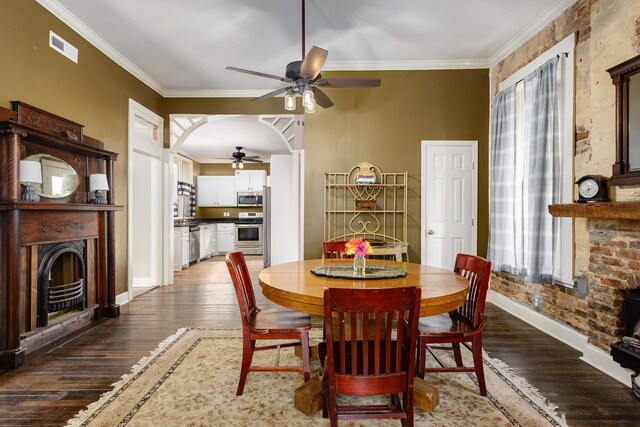  - dining area with arched walkways, a fireplace, wood-type flooring, visible vents, and ornamental molding