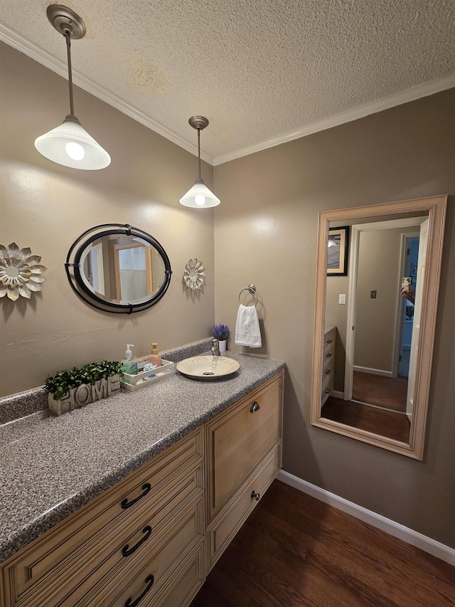  - bathroom featuring wood finished floors, vanity, a textured ceiling, and crown molding