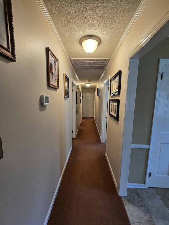  - corridor featuring a textured ceiling, ornamental molding, and dark carpet