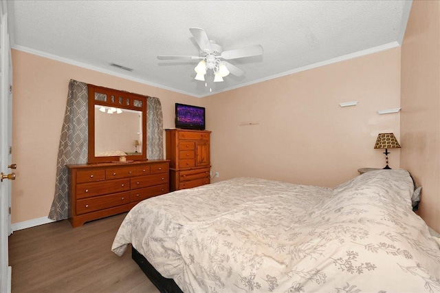 bedroom featuring hardwood / wood-style flooring, crown molding, and a textured ceiling