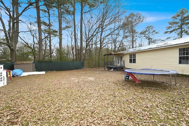 view of yard featuring a trampoline, a shed, and a deck