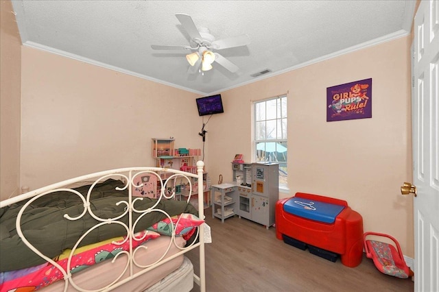 bedroom featuring ceiling fan, wood-type flooring, ornamental molding, and a textured ceiling