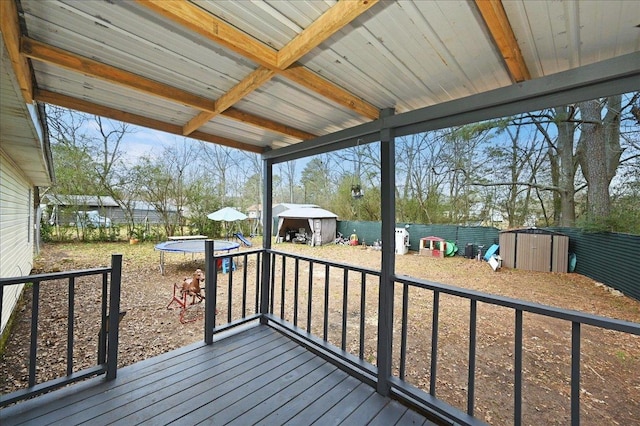 wooden deck featuring a trampoline and a storage unit