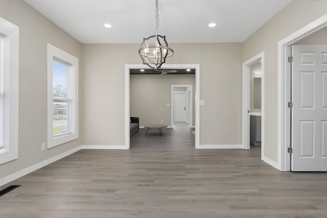  - unfurnished dining area featuring a chandelier, light wood finished floors, recessed lighting, and baseboards
