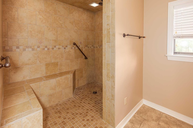 bathroom with baseboards and a tile shower