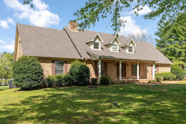 cape cod-style house with brick siding, a chimney, and a front yard