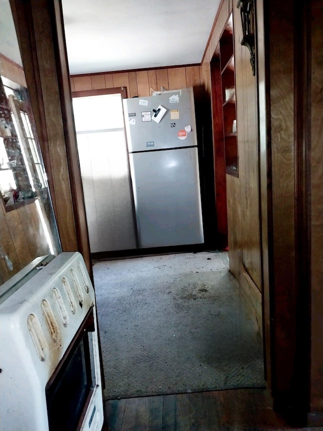 kitchen featuring stainless steel refrigerator and wood walls