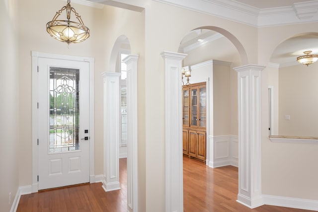 foyer entrance featuring hardwood / wood-style flooring, ornate columns, and ornamental molding