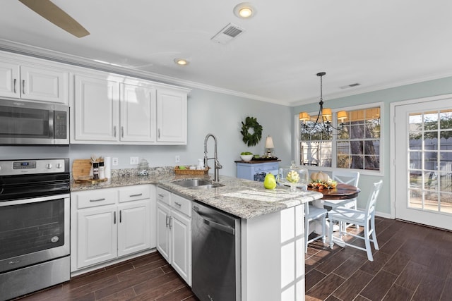 kitchen with appliances with stainless steel finishes, sink, white cabinets, and kitchen peninsula