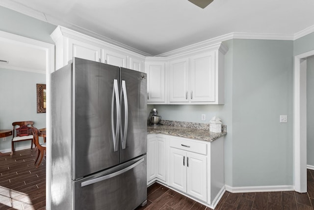 kitchen featuring ornamental molding, light stone countertops, stainless steel refrigerator, and white cabinets