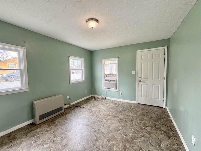 empty room with a textured ceiling, heating unit, and cooling unit