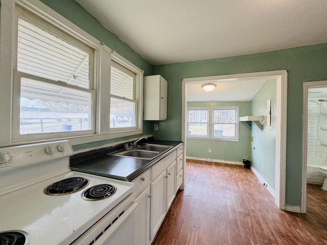 kitchen featuring white cabinets, electric stove, sink, and hardwood / wood-style floors