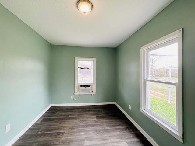 spare room featuring dark hardwood / wood-style flooring, cooling unit, and a healthy amount of sunlight