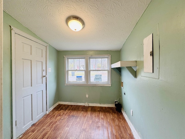 laundry area featuring hookup for an electric dryer, a textured ceiling, and hardwood / wood-style flooring