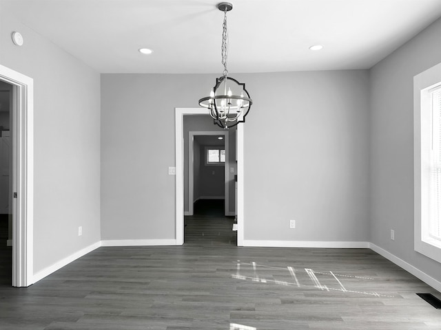 unfurnished dining area with dark hardwood / wood-style flooring and a chandelier