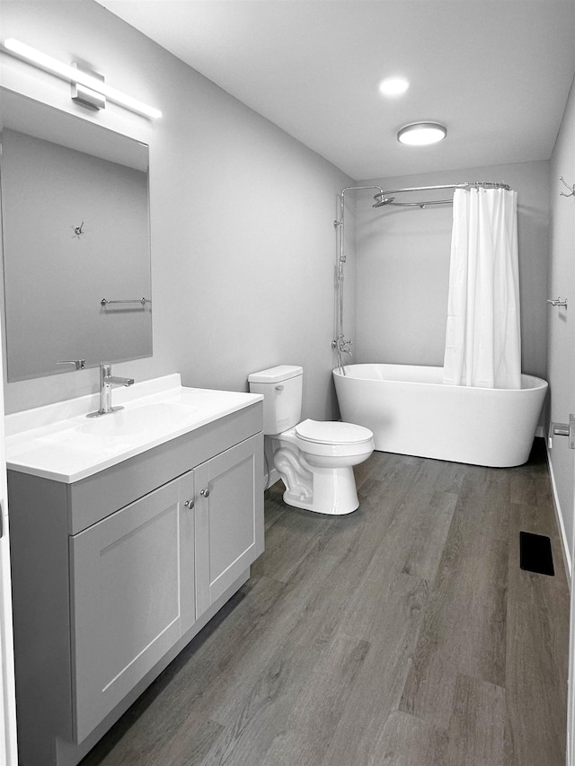 bathroom featuring hardwood / wood-style floors, vanity, toilet, and a bathing tub