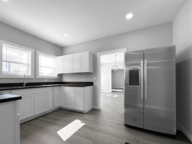 kitchen featuring white cabinetry, stainless steel fridge with ice dispenser, sink, and pendant lighting