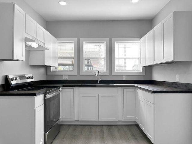 kitchen featuring sink, white cabinets, stainless steel electric range, and hardwood / wood-style flooring