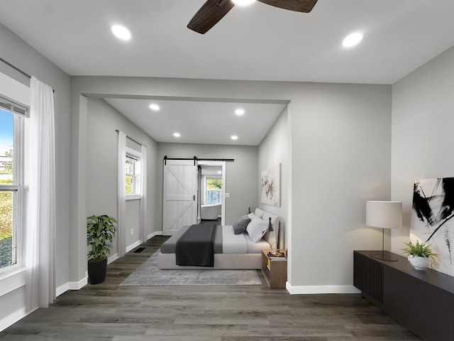 interior space with a barn door, ceiling fan, and dark hardwood / wood-style floors