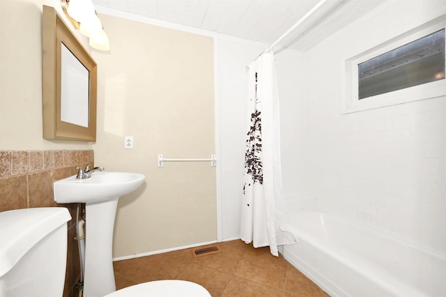 bathroom with tile walls, visible vents, toilet, shower / bathtub combination with curtain, and tile patterned flooring