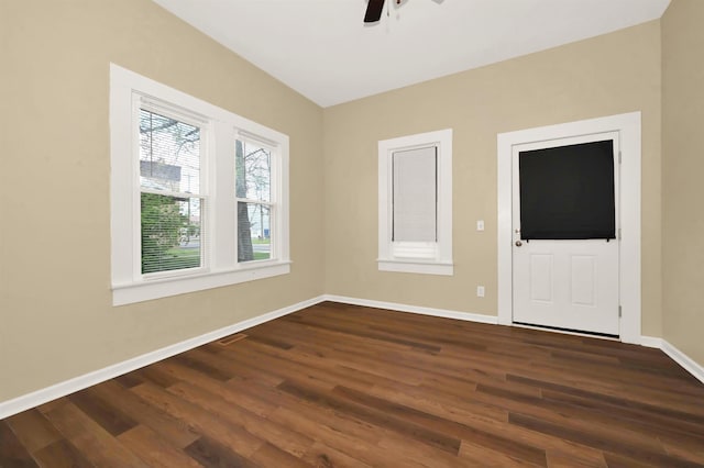 unfurnished room with baseboards, dark wood-style floors, visible vents, and ceiling fan