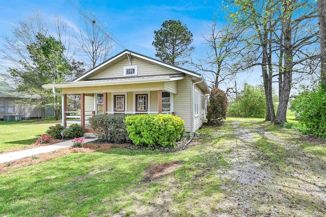 view of front facade featuring driveway, central AC unit, a porch, and a front yard