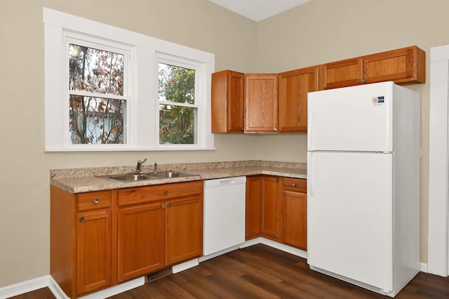 kitchen with light countertops, a sink, brown cabinetry, and white appliances