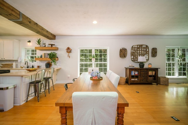 dining space with beam ceiling, light hardwood / wood-style flooring, and ornamental molding