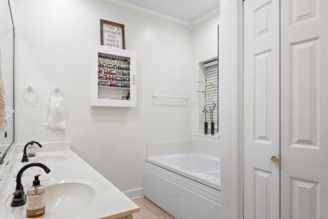 bathroom with tile patterned floors, ornamental molding, a bathing tub, and vanity