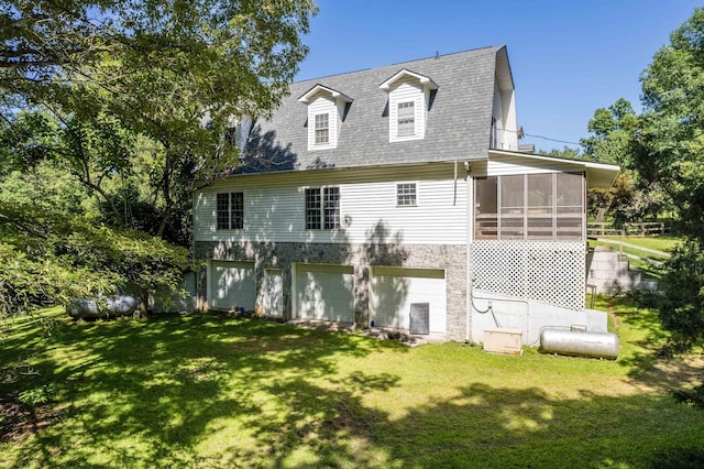 rear view of house with a sunroom, a garage, and a lawn